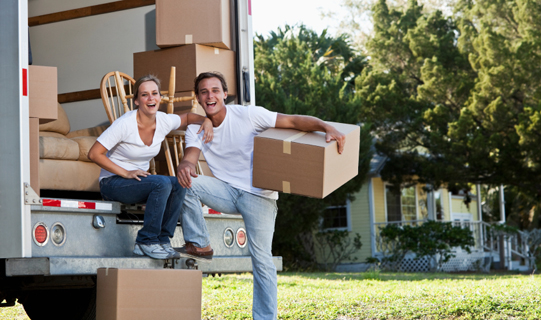 Couple taking a break loading or unloading moving van with boxes and furniture